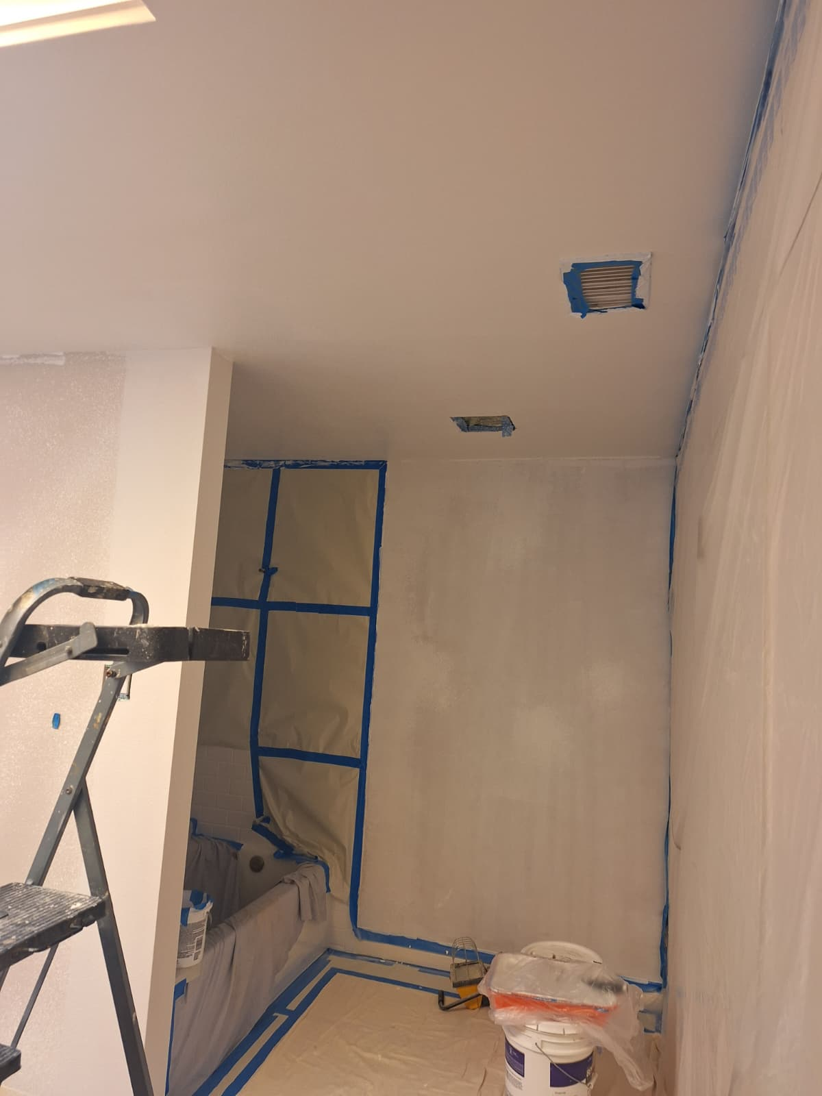 Bathroom walls masked with tape and plastic before painting