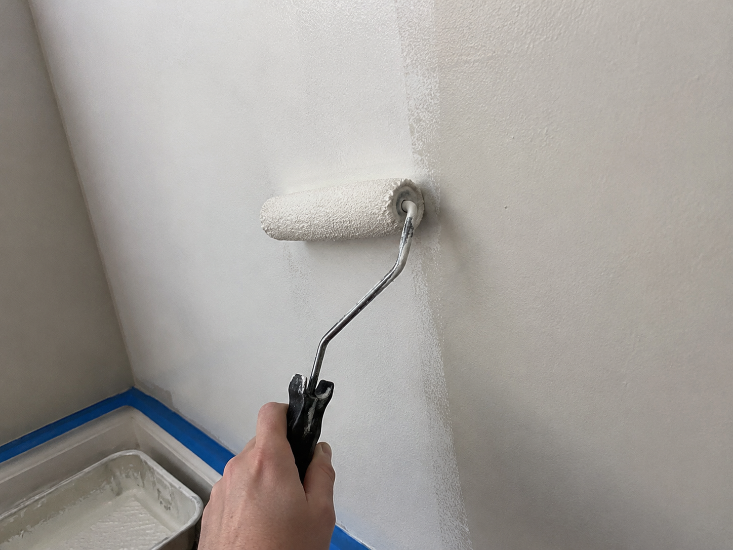 Paint roller applying paint to an interior wall